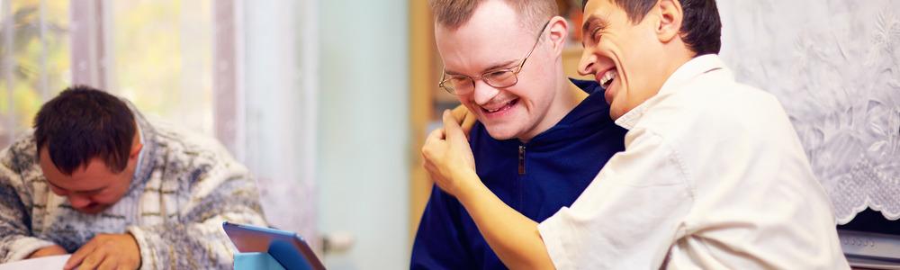 Two men hugging in a social home setting.