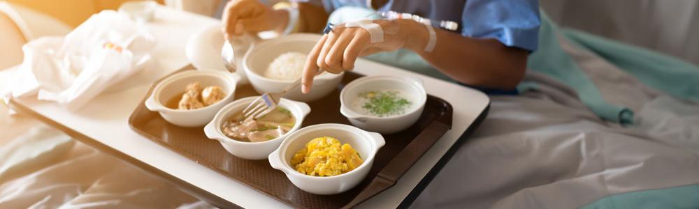 Person eating a meal in a hospital bed.