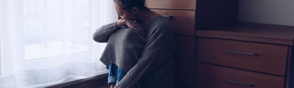 Depressed woman curled up on the floor.