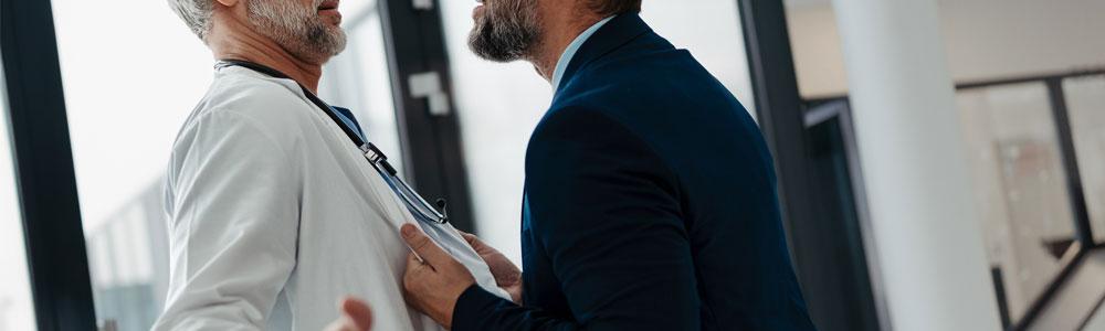 Man in suit being aggressive towards doctor