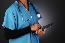 A doctor in scrubs with a stethescope and a tablet device
