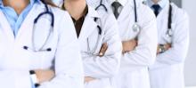 A row of doctors in white coats. Their faces cannot be seen.