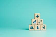 A pile of blocks with different medical symbols on them, such as a stephoscope and an IV drip.