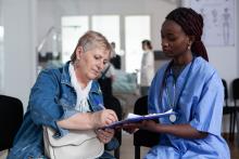 A woman signs a form given to her by a female health worker.