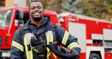 Firefighter smiling in front of a fire engine.