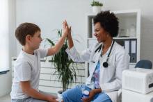 Child hi fives female doctor