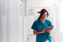 Female doctor wearing scrubs using a tablet.