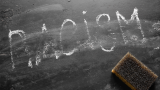 Racism written on a blackboard and rubbed out.