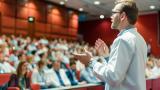 A doctor delivers a speech to a room of medical professionals.