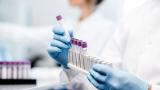 Scientist putting test tubes into a holder in a lab.