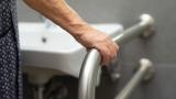 Elderly woman using handrail in bathroom