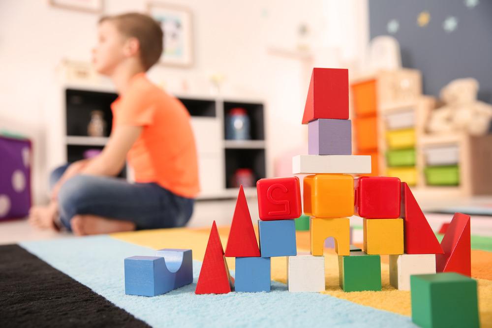 A tower of block toys in the centre of the image, a little boy is in the background out of focus.