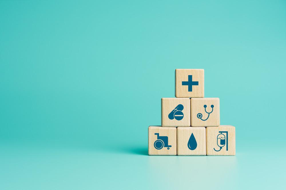 A pile of blocks with different medical symbols on them, such as a stephoscope and an IV drip.