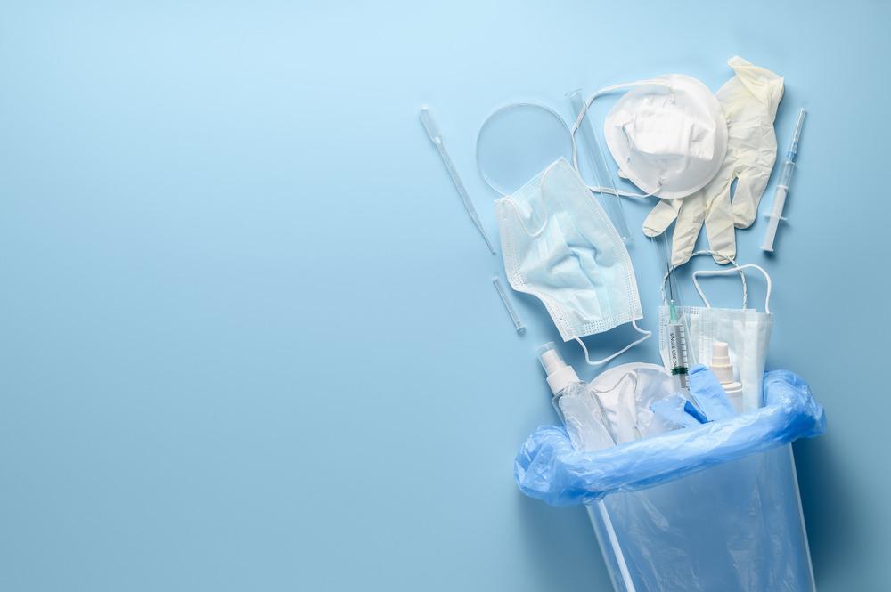 A bag of medical equipment spills out onto a blue background. It includes a mask, gloves, and a syringe.