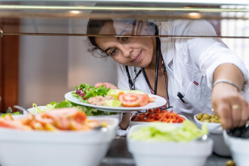 A health worker stocks up for lunch at a hospital canteen. She is eating salad-type food.