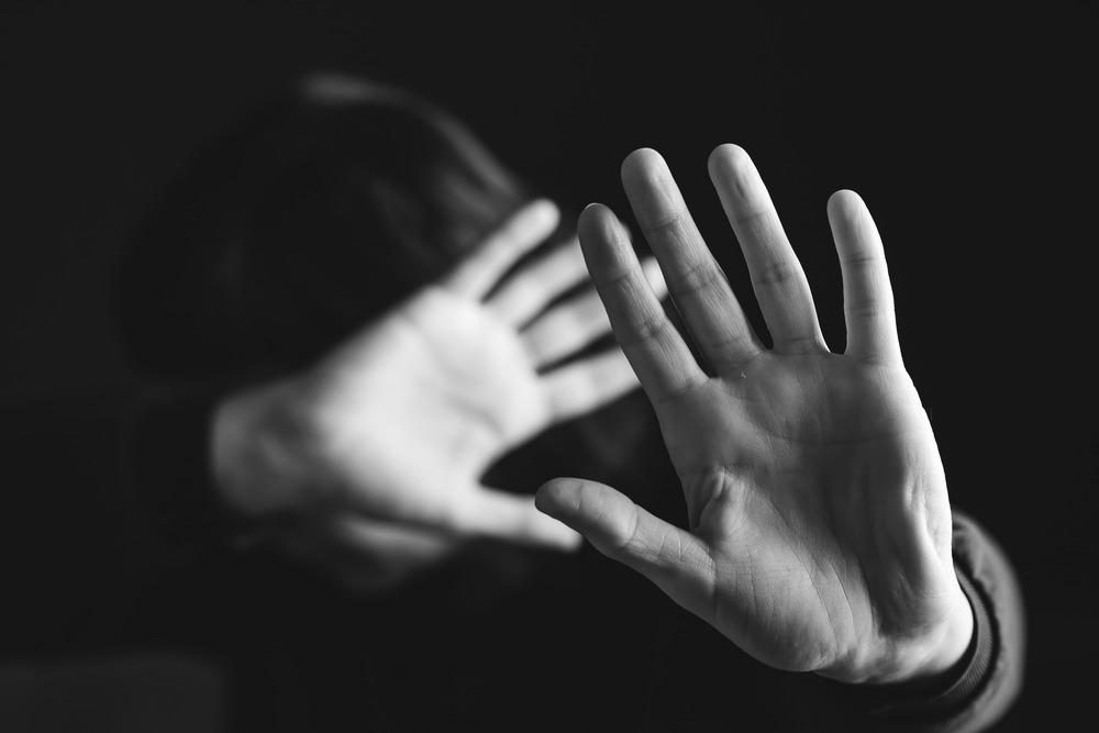 A young person holds up their hands in defence. The image is in black and white.
