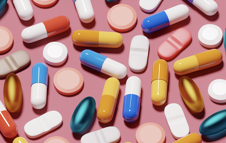 A variety of pills on a pink background.