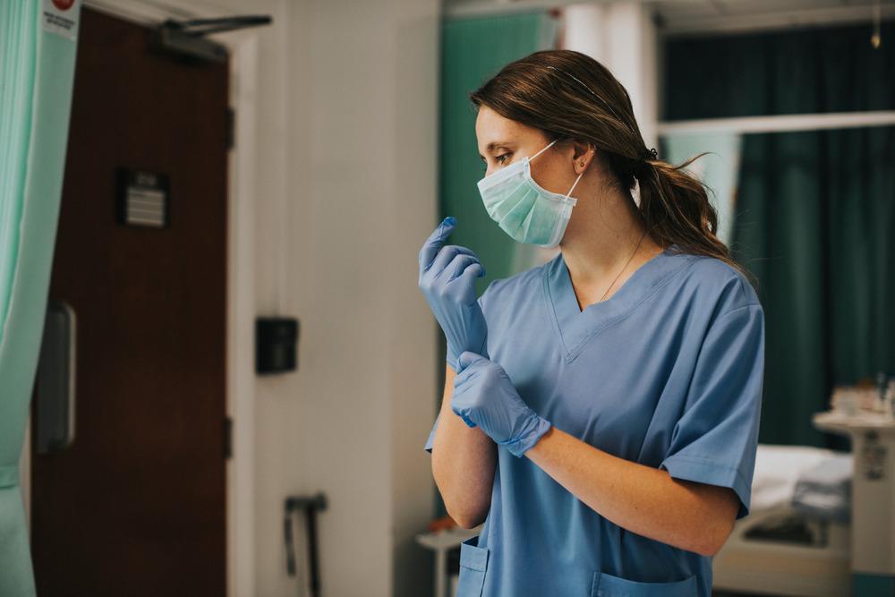 A nurse puts on gloves.