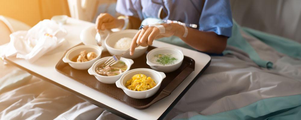 Person eating a meal in a hospital bed.