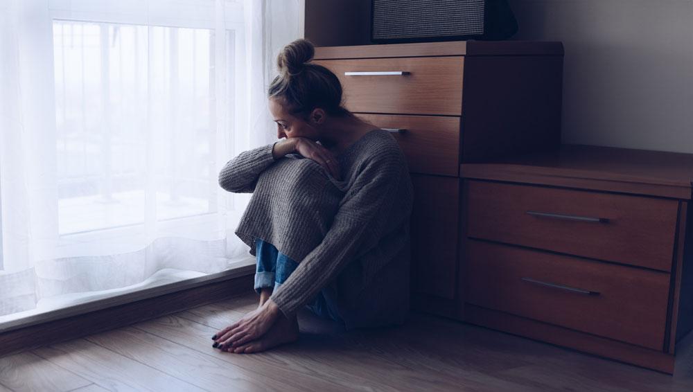Depressed woman curled up on the floor.