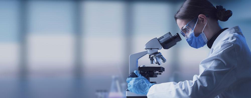 Scientist in a lab uses a microscope.