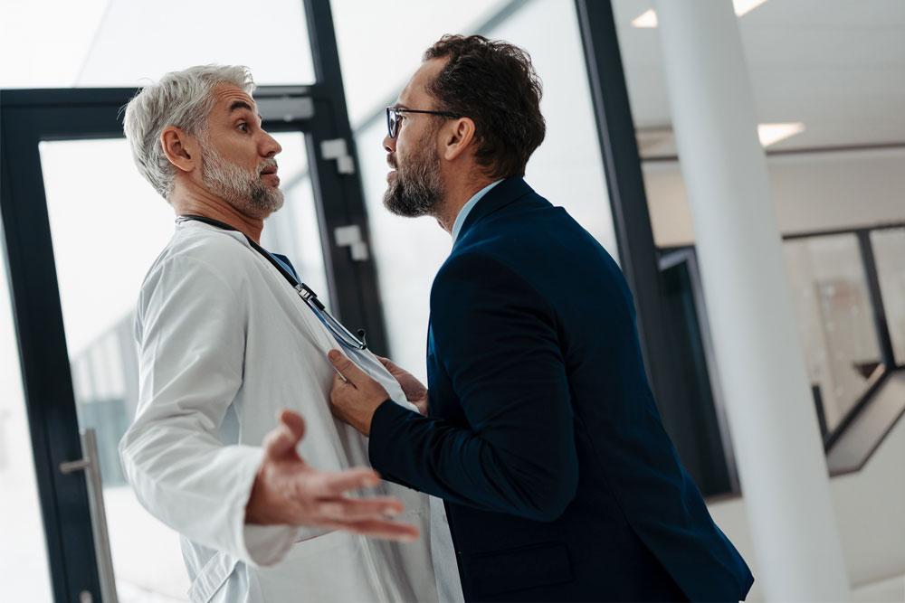 Man in suit being aggressive towards doctor